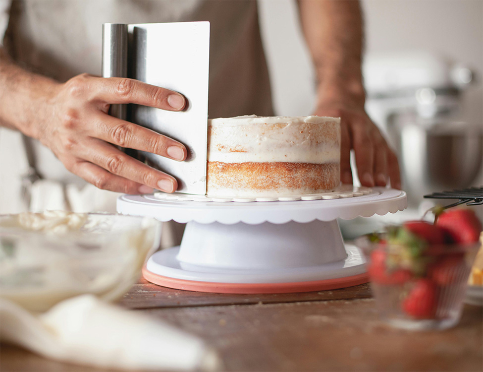 pastry chef trimming a cake on a turnable